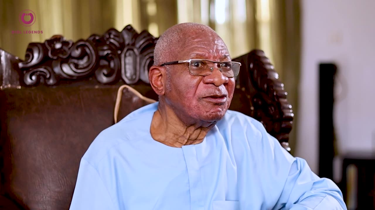 Prof. Imevbore seated in a carved chair at home, speaking to camera